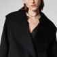 Black cropped wool coat close-up with wide collar, lapels, and buttoned front