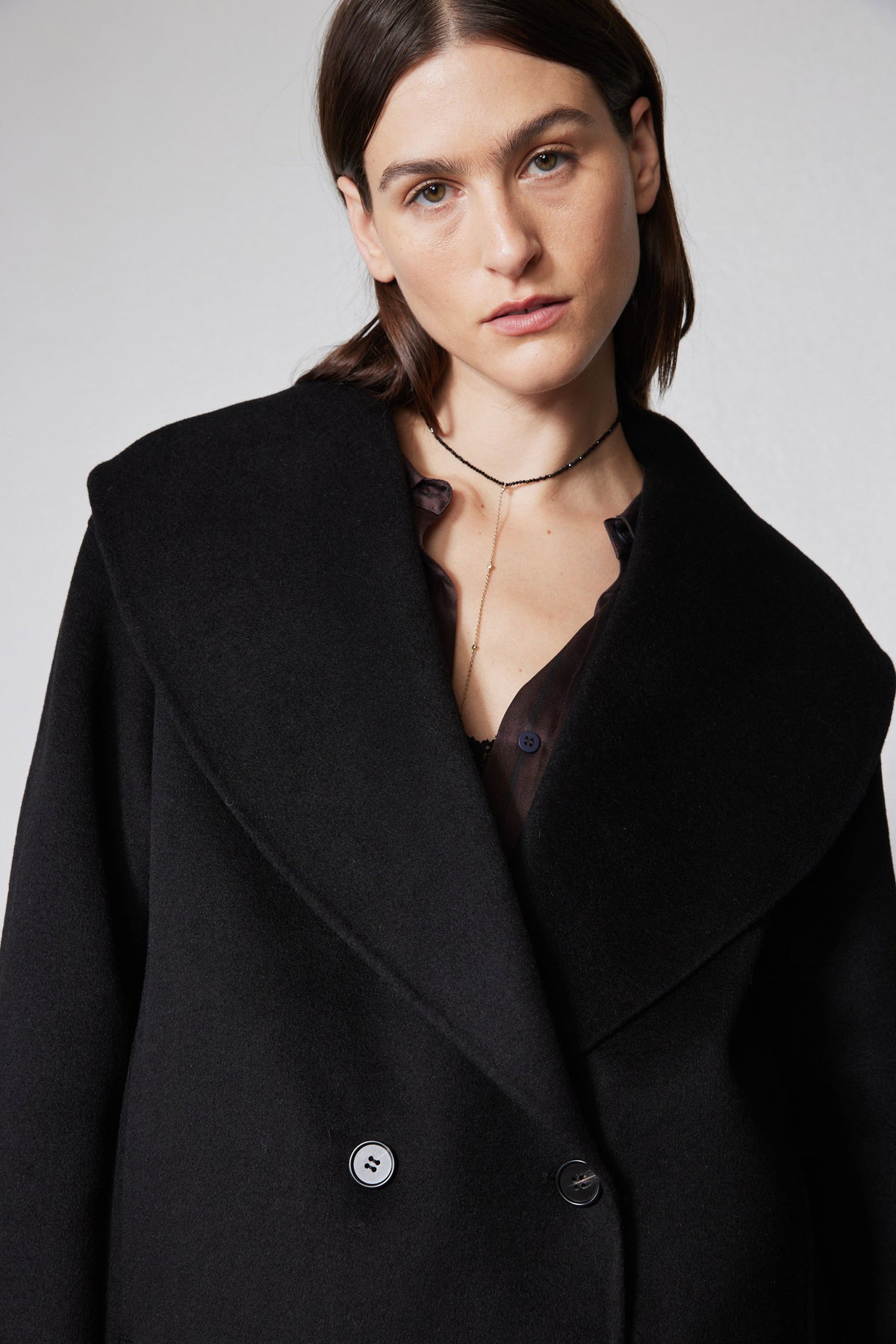 Black cropped wool coat close-up with wide collar, lapels, and buttoned front