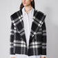 Cropped plaid wool coat with notched lapels, dark buttons, and structured shoulders