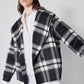 Close-up of plaid wool coat with long sleeves and open front, black/white checks