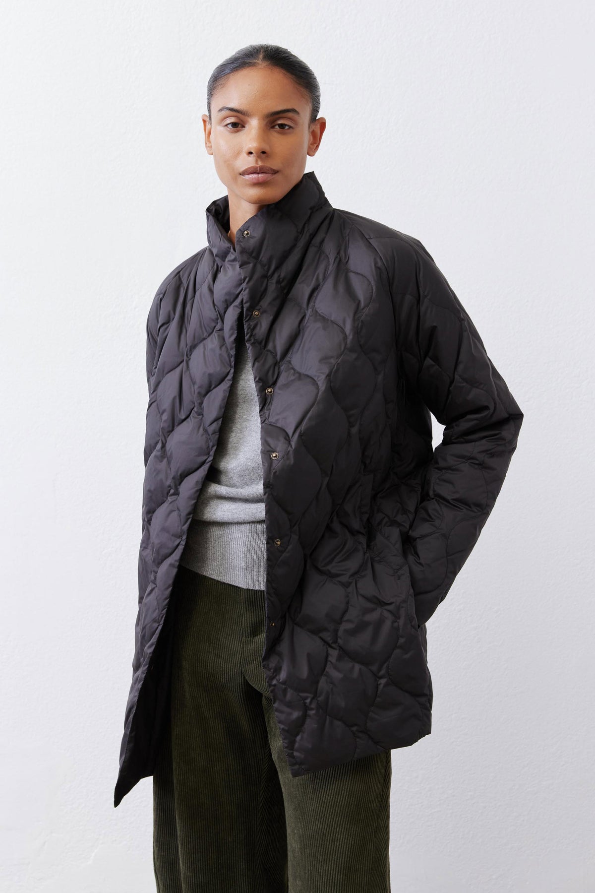 Black down puffer coat with stand collar, diamond quilting, and button placket.