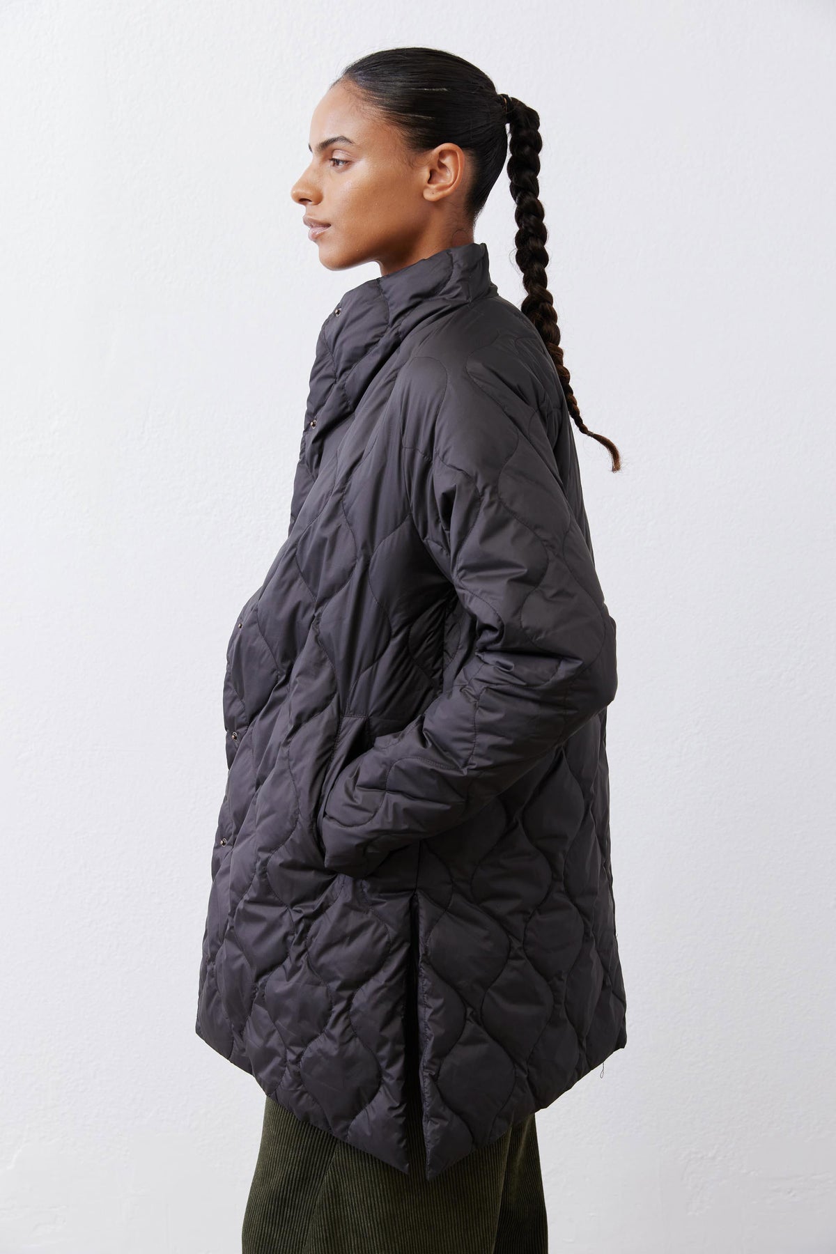 Black long puffer coat with diamond quilting and slanted side pockets.