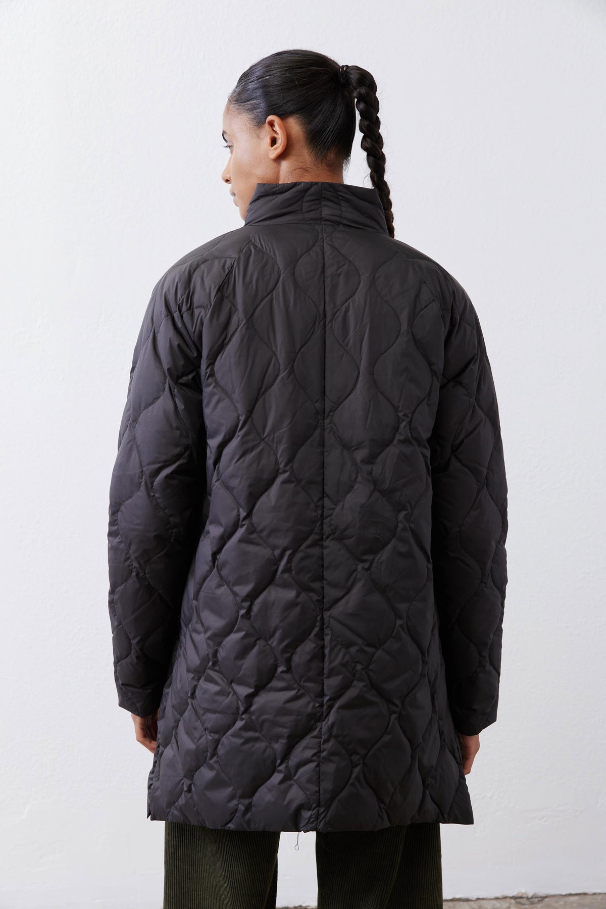 Black long down puffer coat, diamond-quilted back with vented hem.