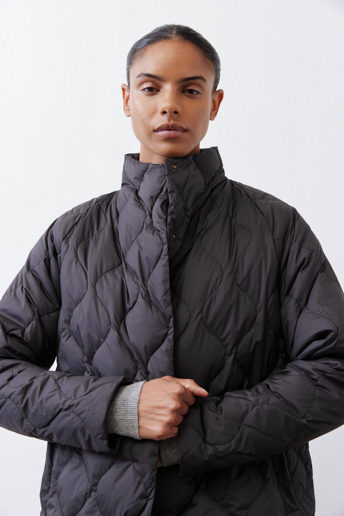 Black down puffer coat with diamond quilting and stand collar; front closure.