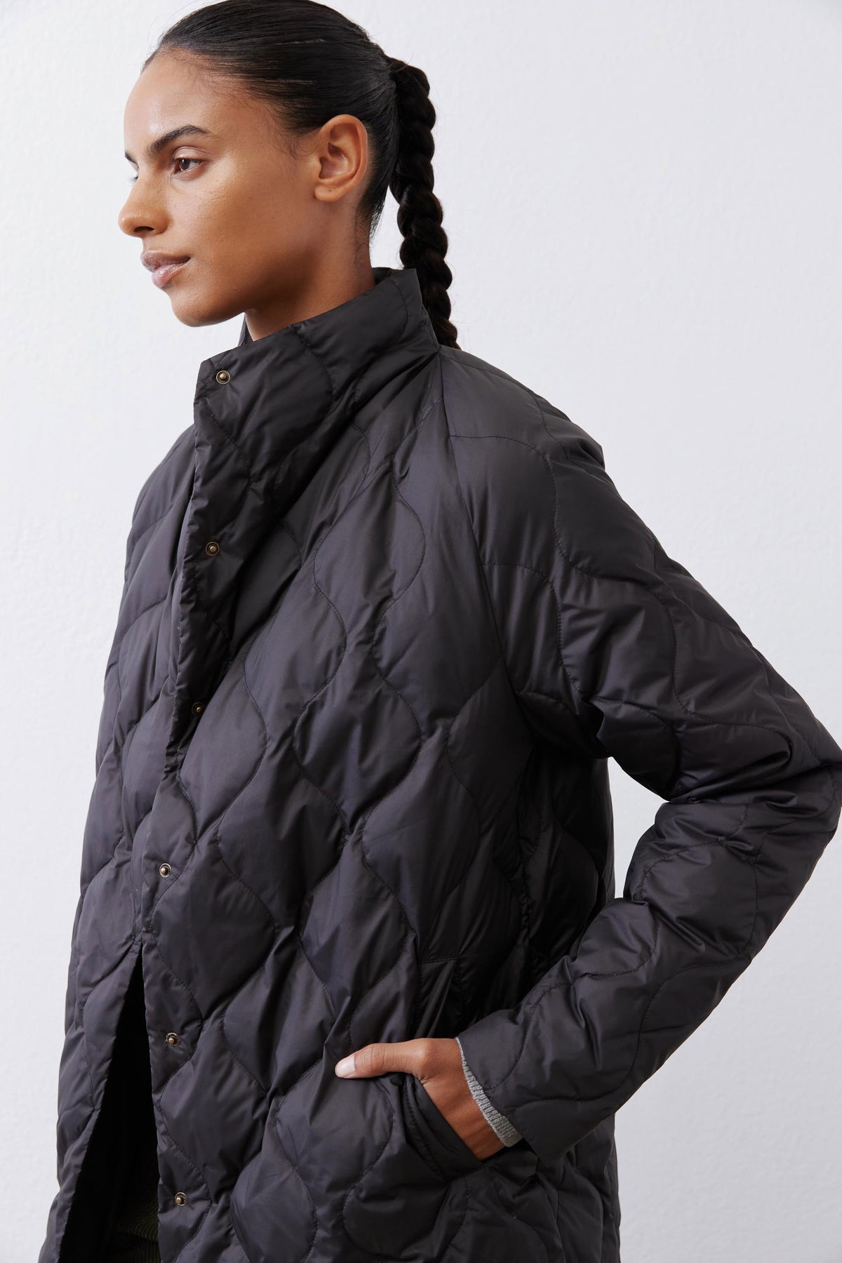 Black down puffer coat sleeve and side pockets with diamond quilting and snap buttons.