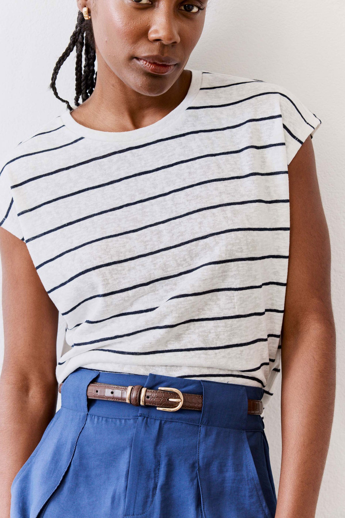 Chocolate croc-embossed belt with oval buckle on blue skirt-like pants at waist