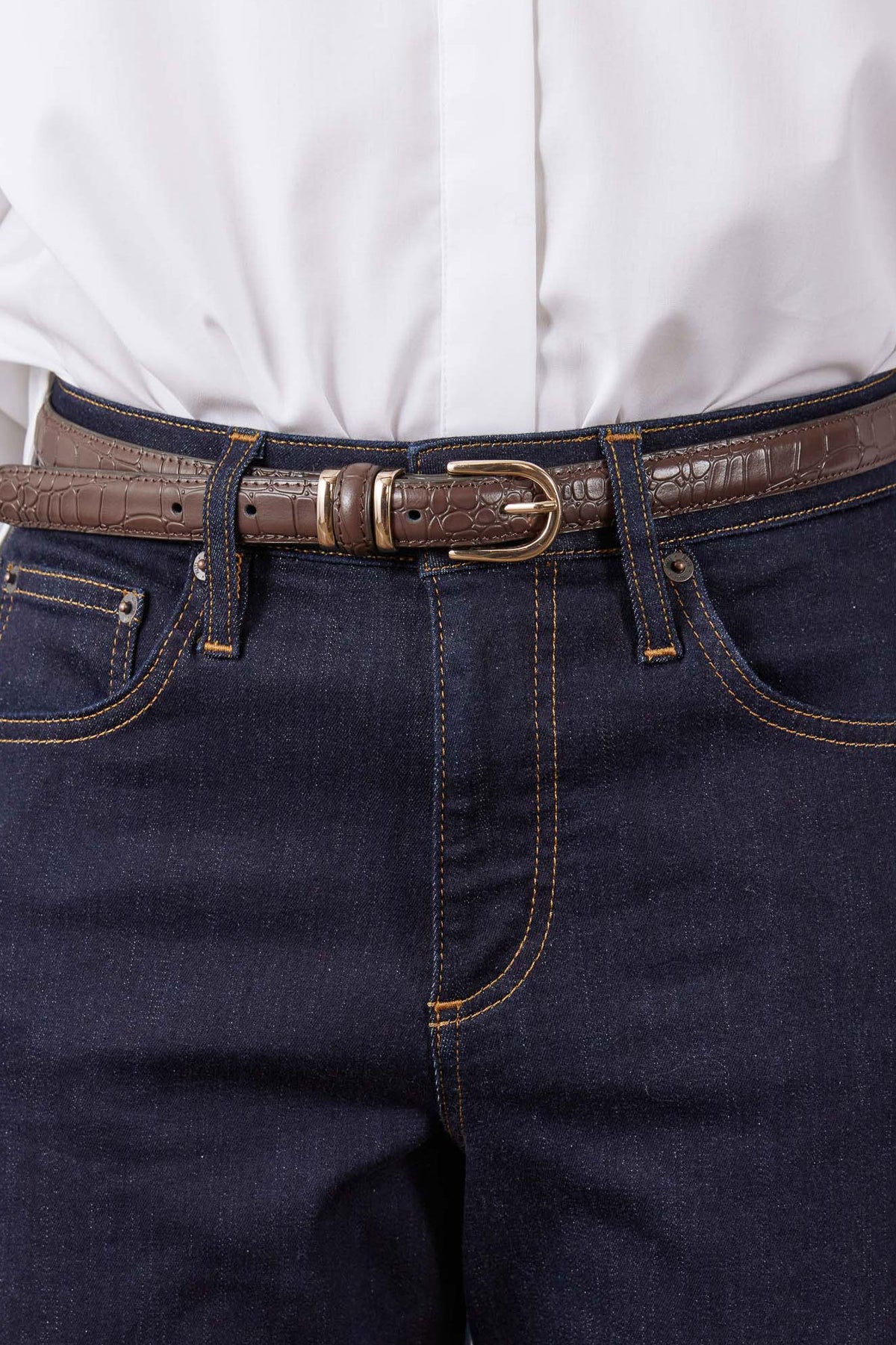 Chocolate croc-embossed belt with oval buckle close-up on dark denim jeans