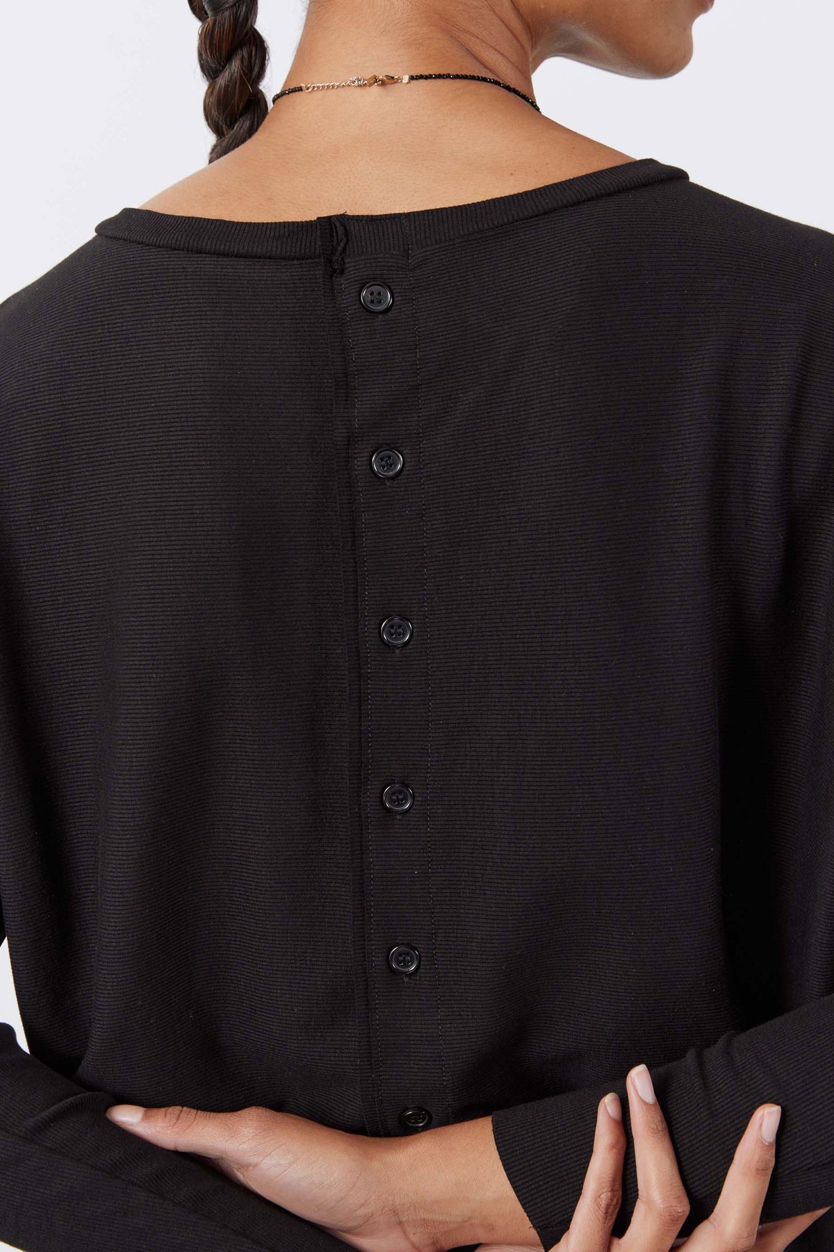 Back of black long-sleeve top showing button placket and gathered neckline