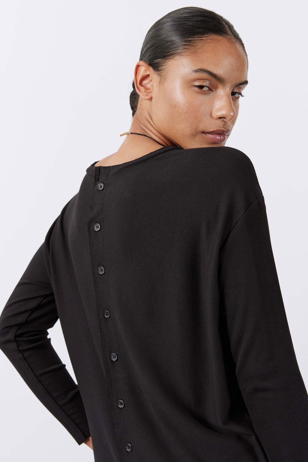 Black long-sleeve top back close-up with vertical button placket
