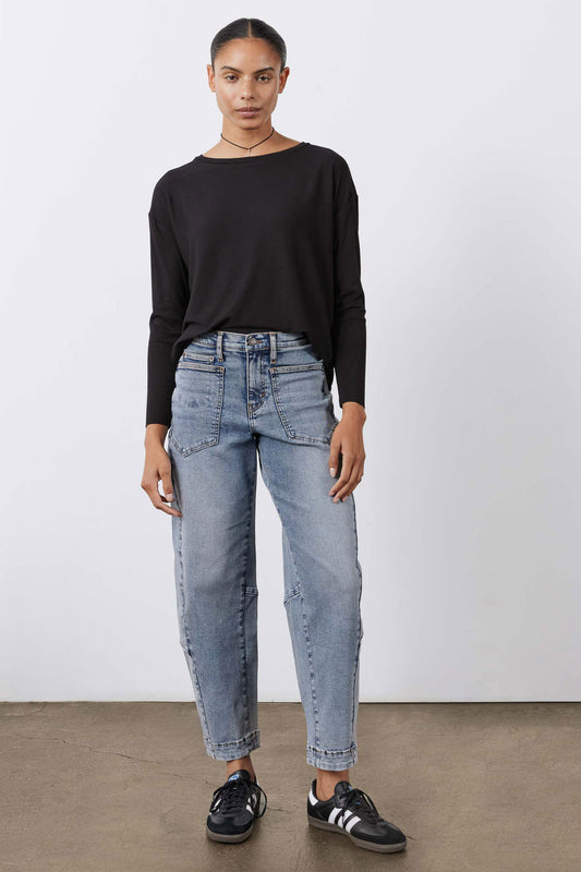 Black long-sleeve top with round neck, worn with light-wash jeans.