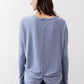 Light blue long-sleeve top with button placket at back and twisted hem