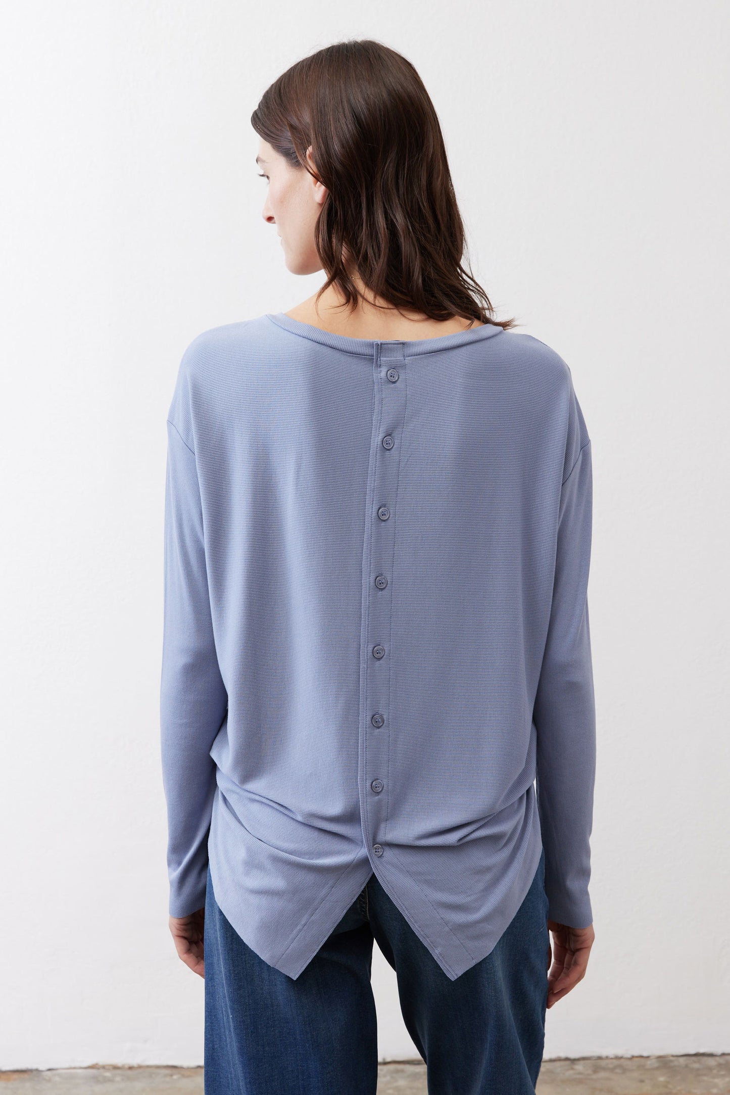 Light blue long-sleeve top with button placket at back and twisted hem