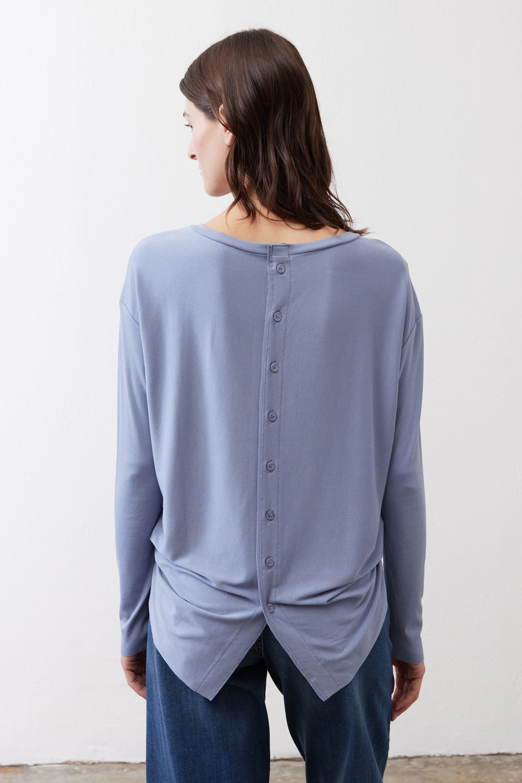 Light blue long-sleeve top with button placket at back and twisted hem