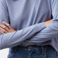 Light blue long-sleeve crewneck top with visible ribbed texture and sleeve cuff