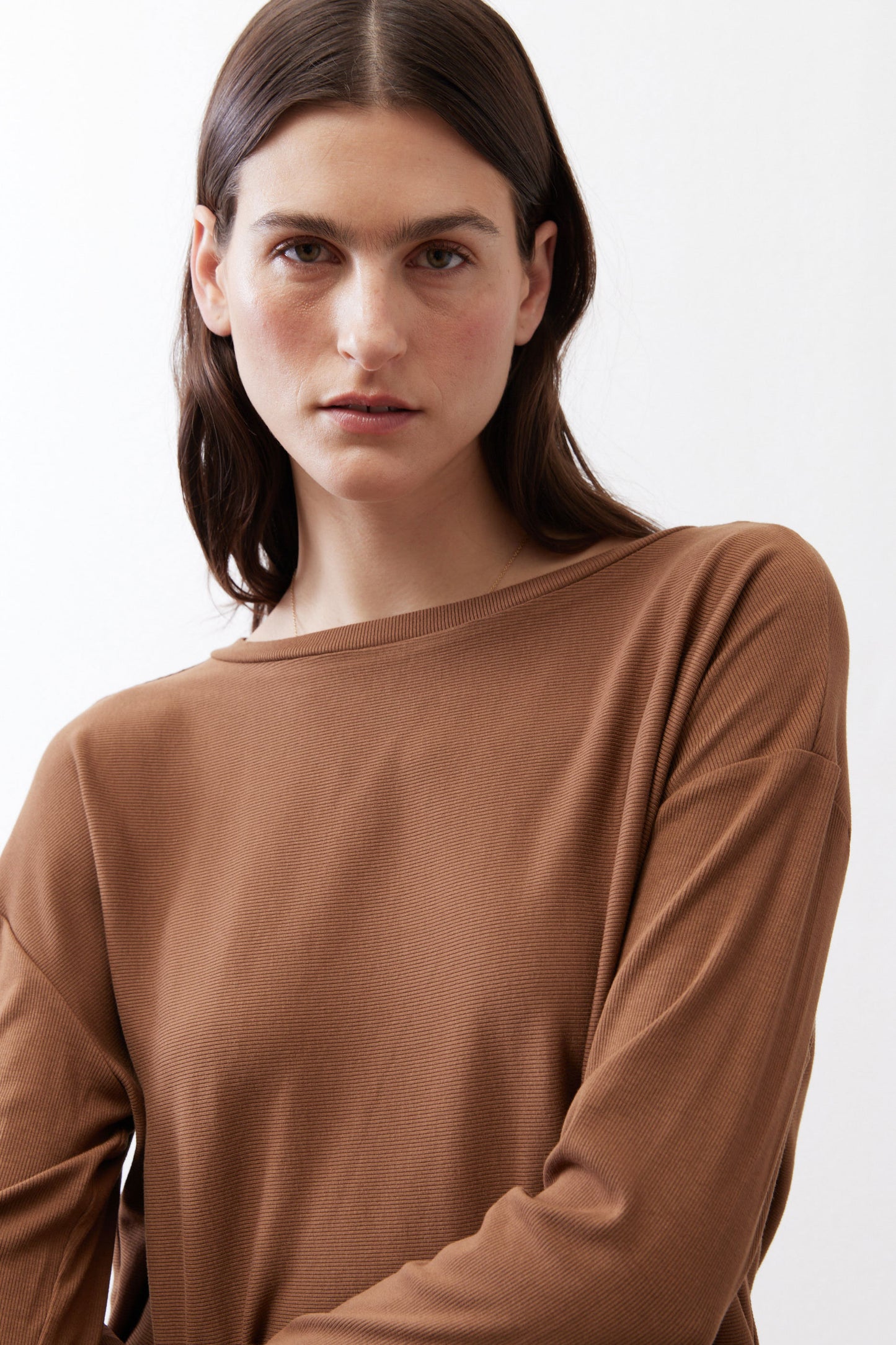 Deep brown crew-neck long-sleeve top close-up, soft drape at shoulders