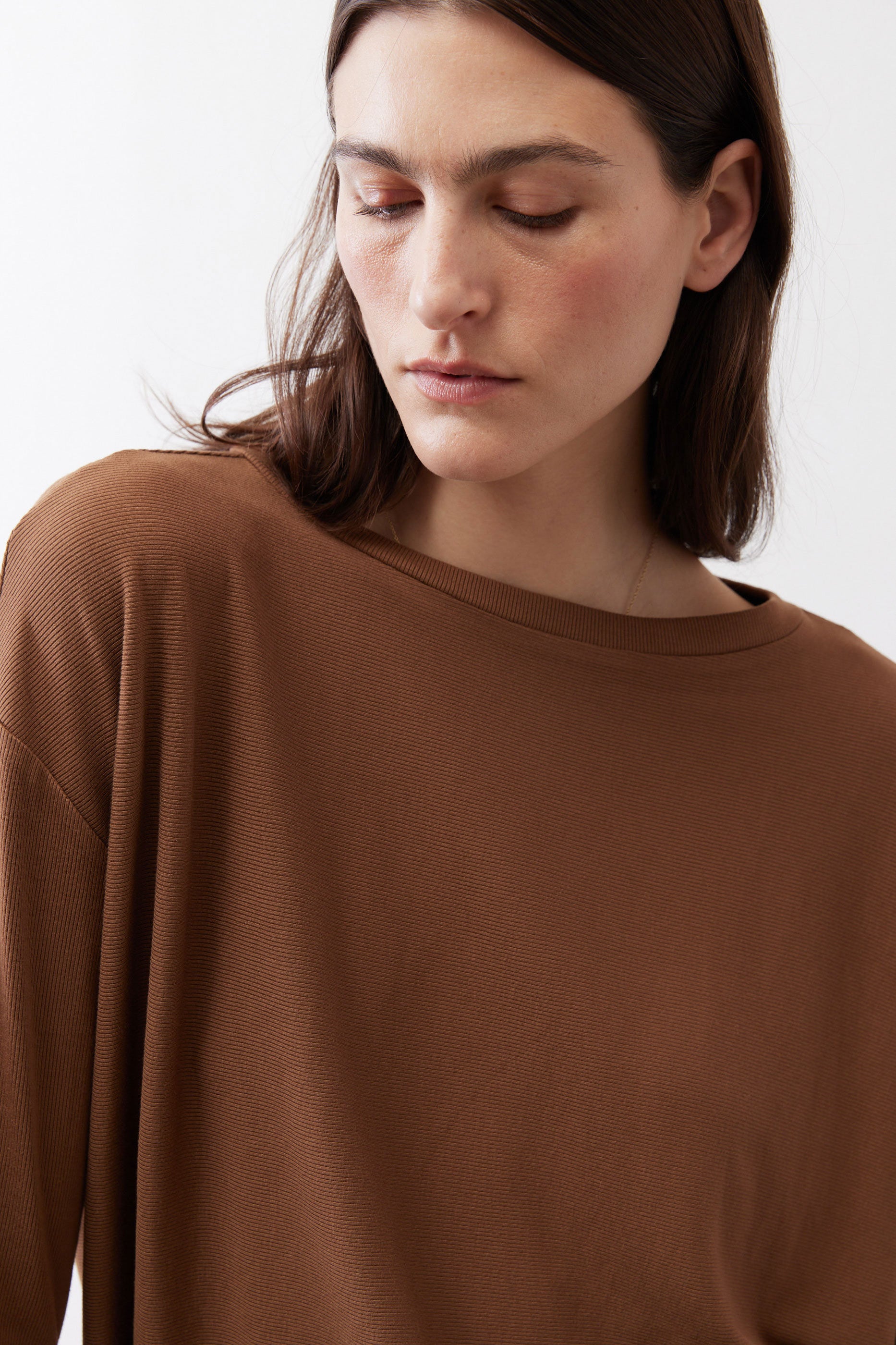 Deep brown crew-neck long-sleeve top close-up, smooth knit fabric