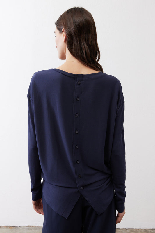 Navy long-sleeve top with back button placket and knotted waist detail.
