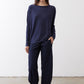 Deep navy long-sleeve top with round neckline and draped waist detail