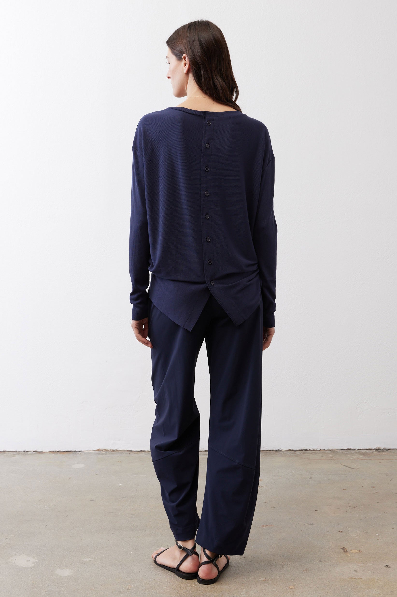Deep navy long-sleeve top back with vertical buttons and knotted back hem