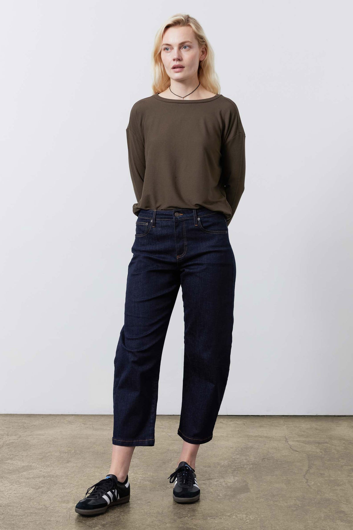 Dark taupe long-sleeve crewneck top worn with high-waist jeans, front view