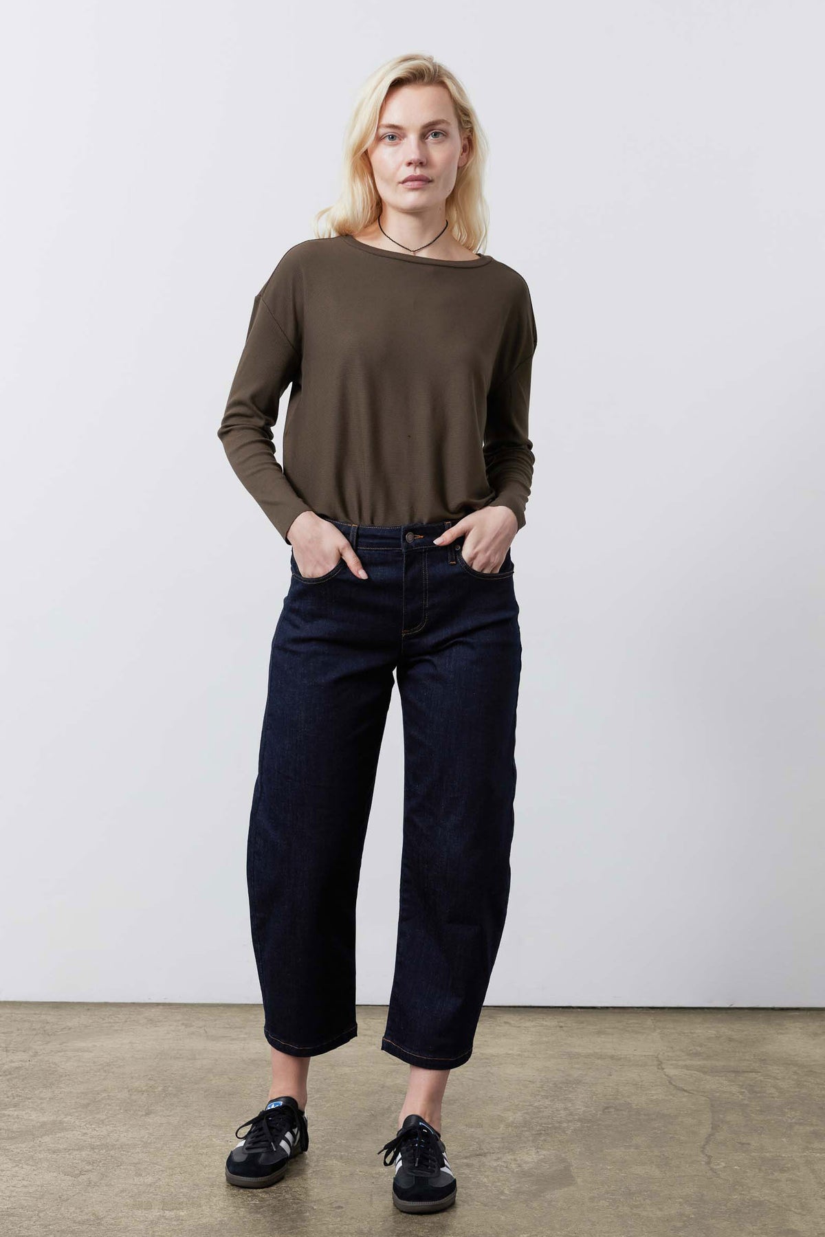 Dark taupe long-sleeve crewneck top with relaxed fit, worn with jeans, front view