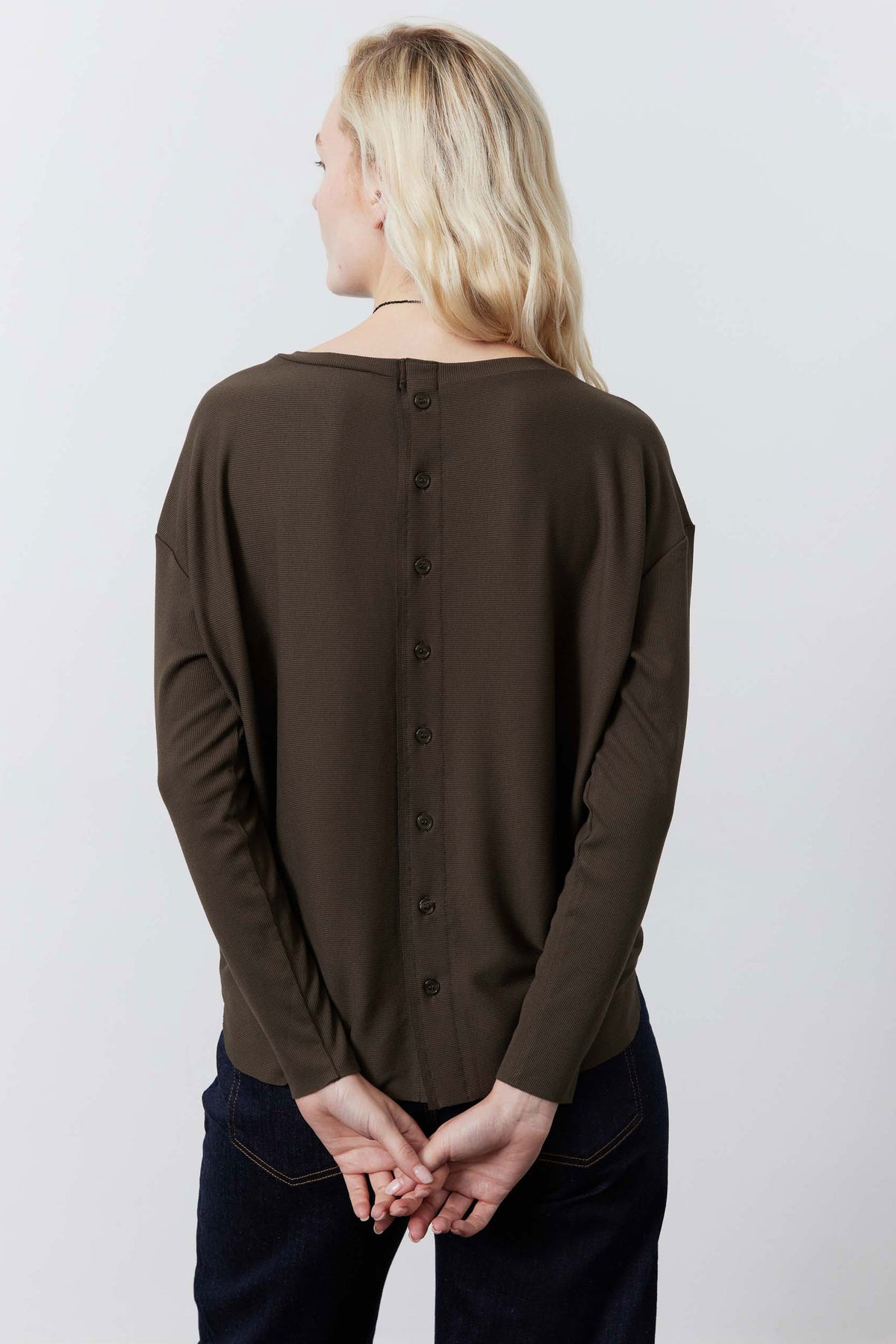 Dark taupe long-sleeve top with buttoned back detail, worn with jeans, back view