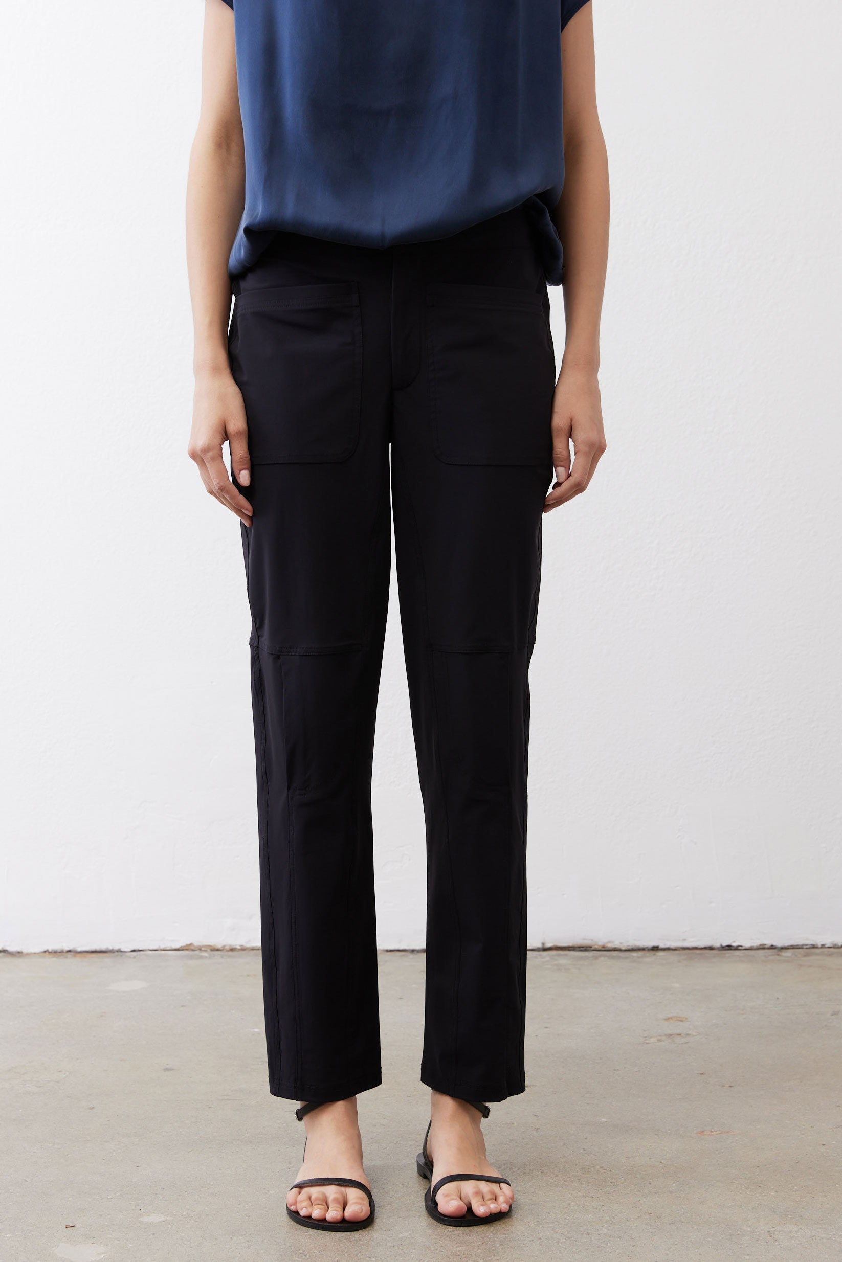 Black slim pants with cargo-style front pockets and straight ankle cuffs