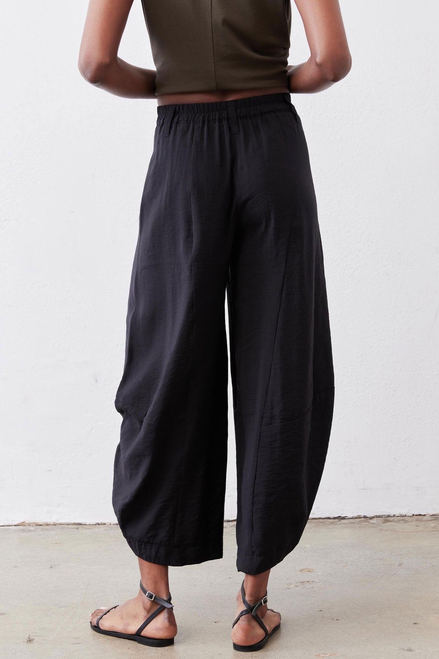 Black wide-leg pants with elastic waistband and loose back drape to ankle hem