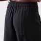 Black wide-leg pants with gathered elastic waistband and smooth, relaxed fabric