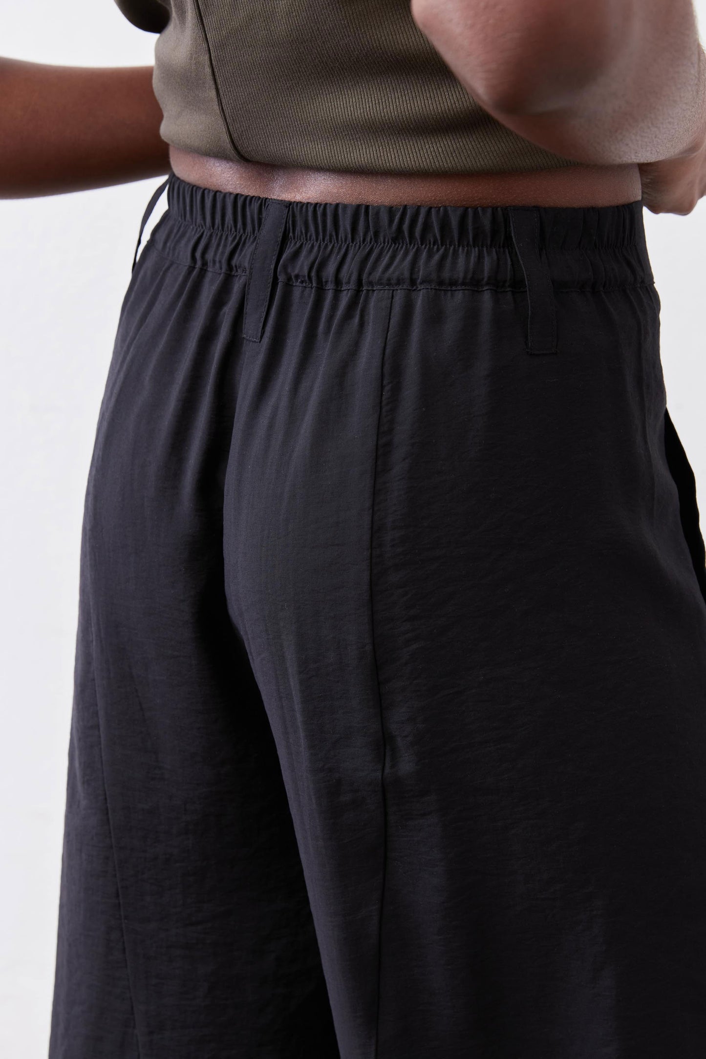 Black wide-leg pants with gathered elastic waistband and smooth, relaxed fabric