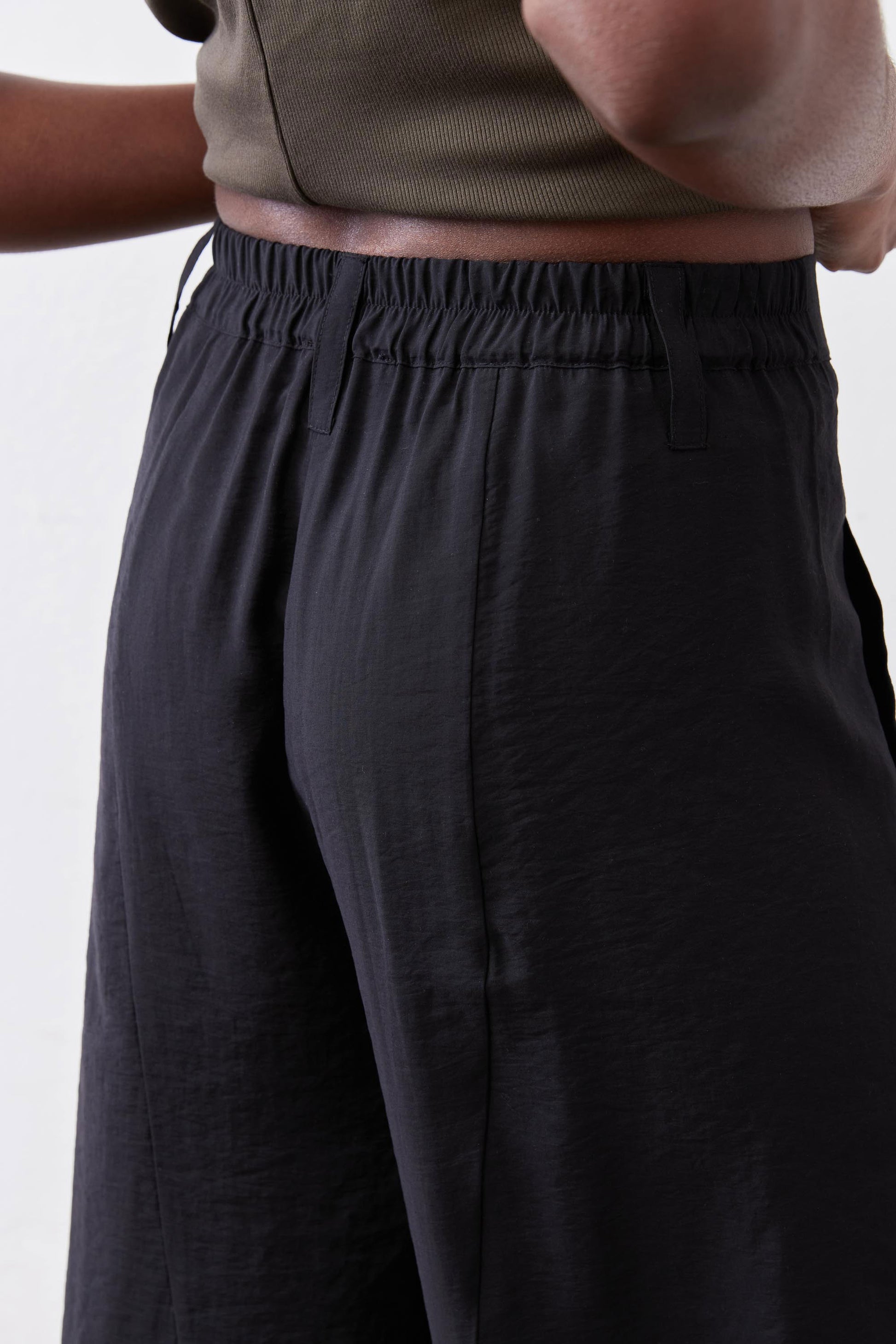 Black wide-leg pants with gathered elastic waistband and smooth, relaxed fabric