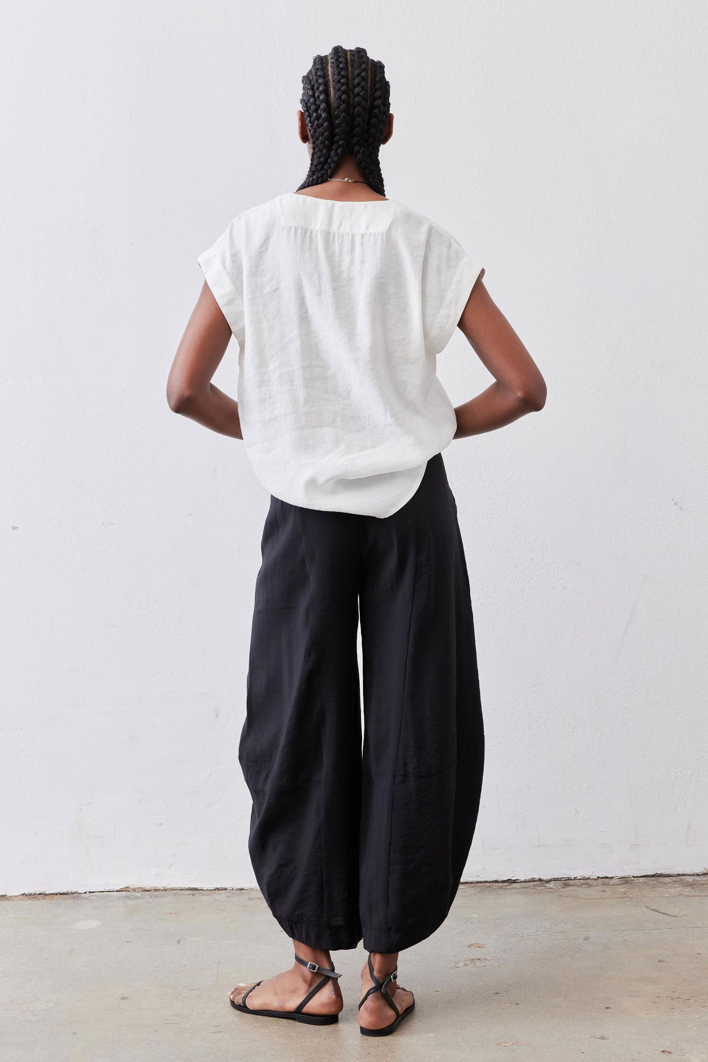 Black wide-leg pants with elastic waistband, back view, relaxed drape to ankle hem