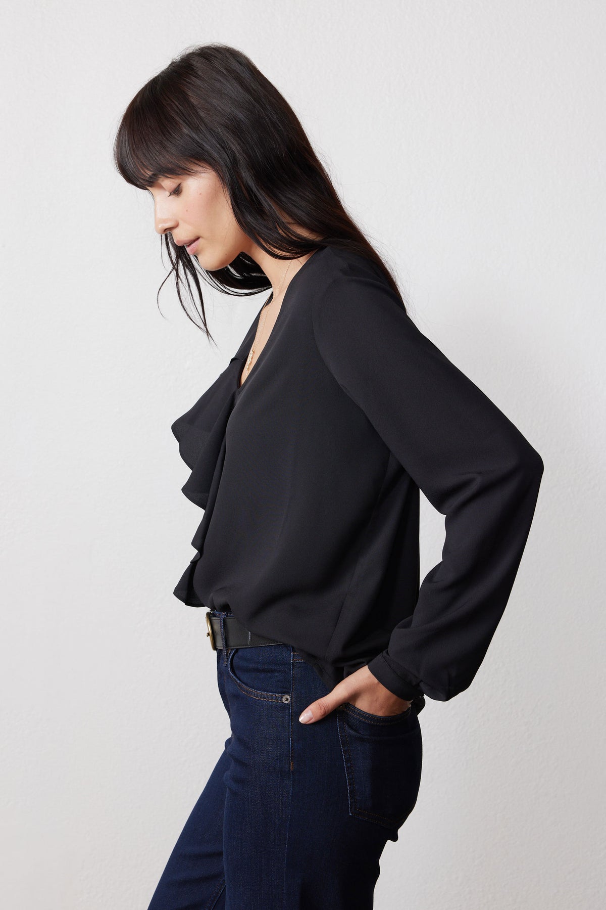 Black long-sleeve V-neck top with flounce ruffle detail, side view