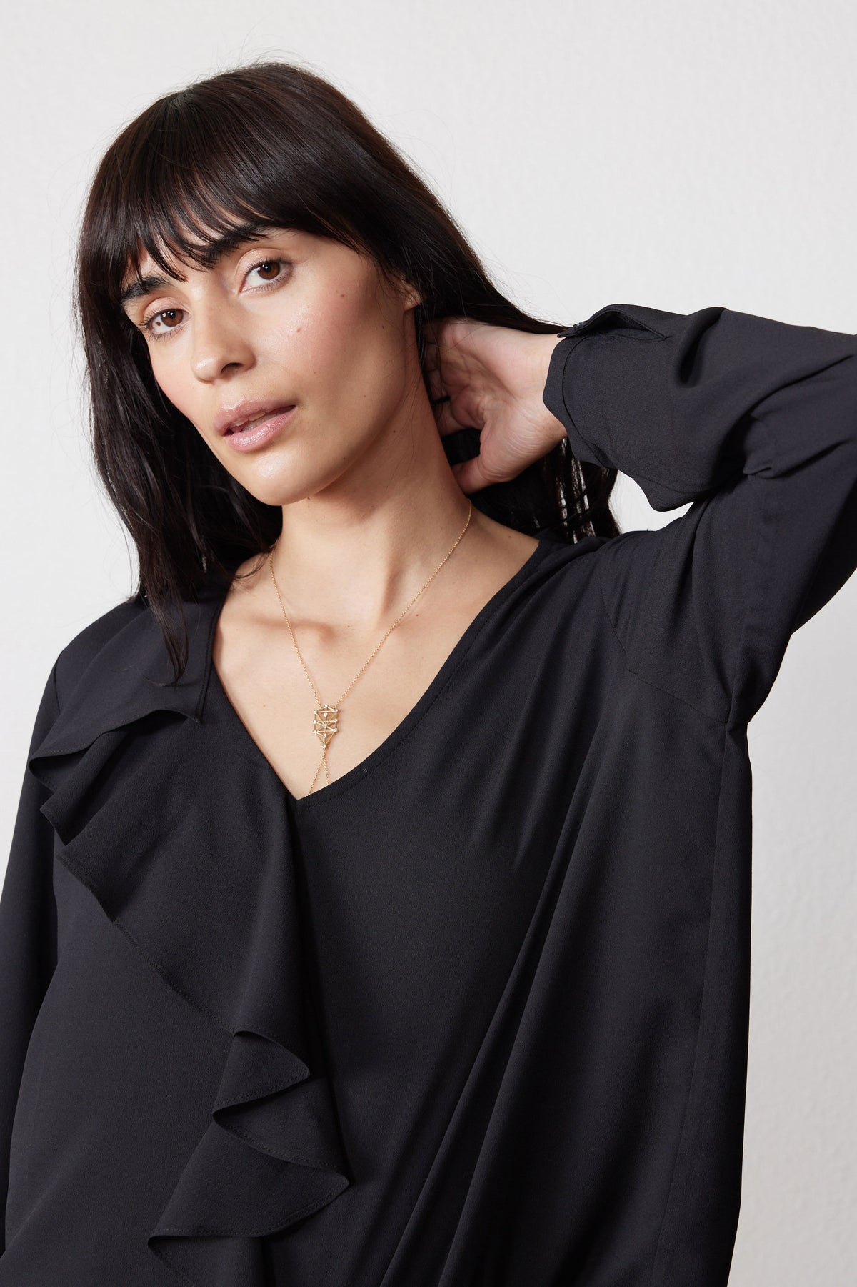 Black flounce V-neck top close-up with ruffled front and long sleeves