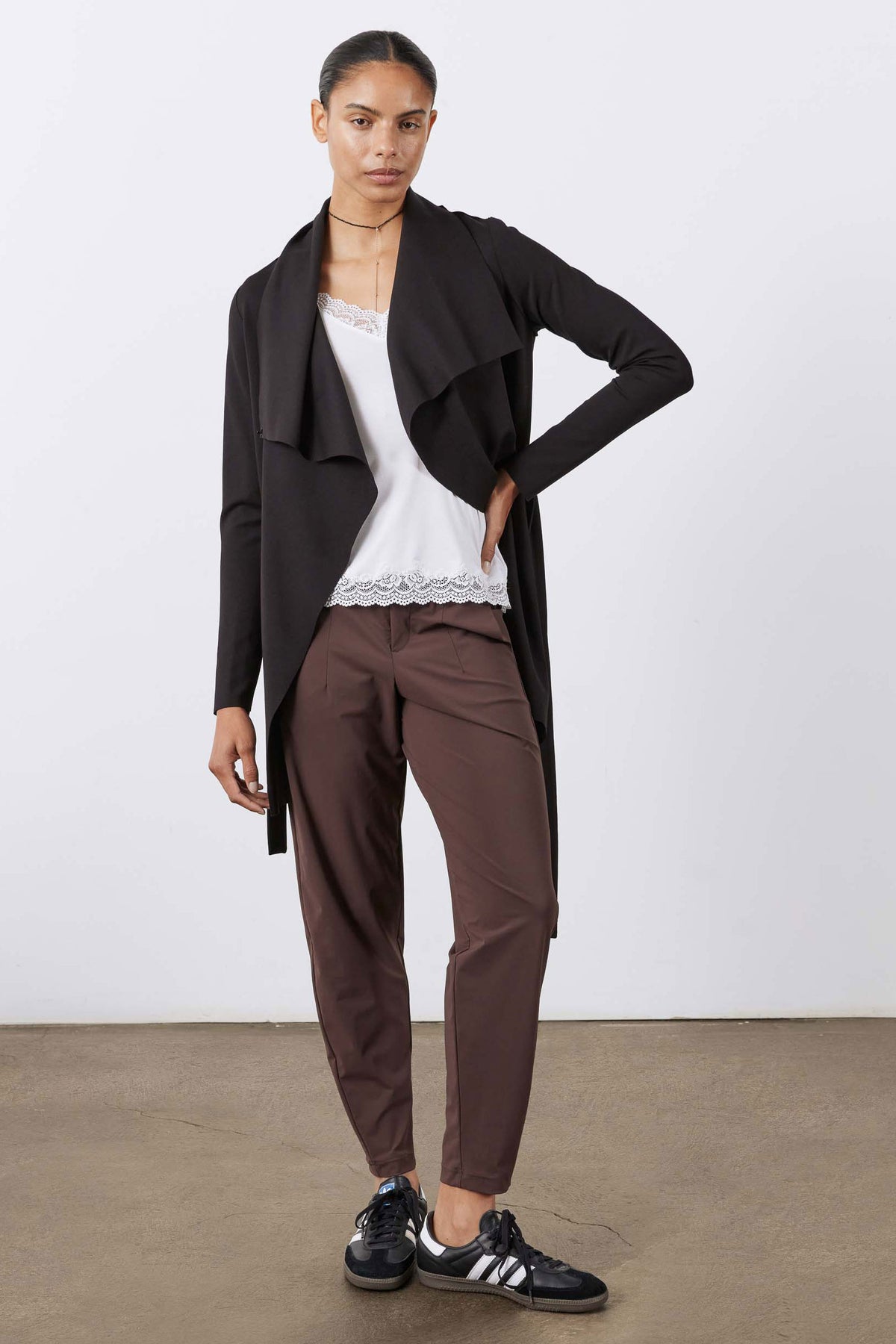 Black draped jacket with high collar and waist belt, side view