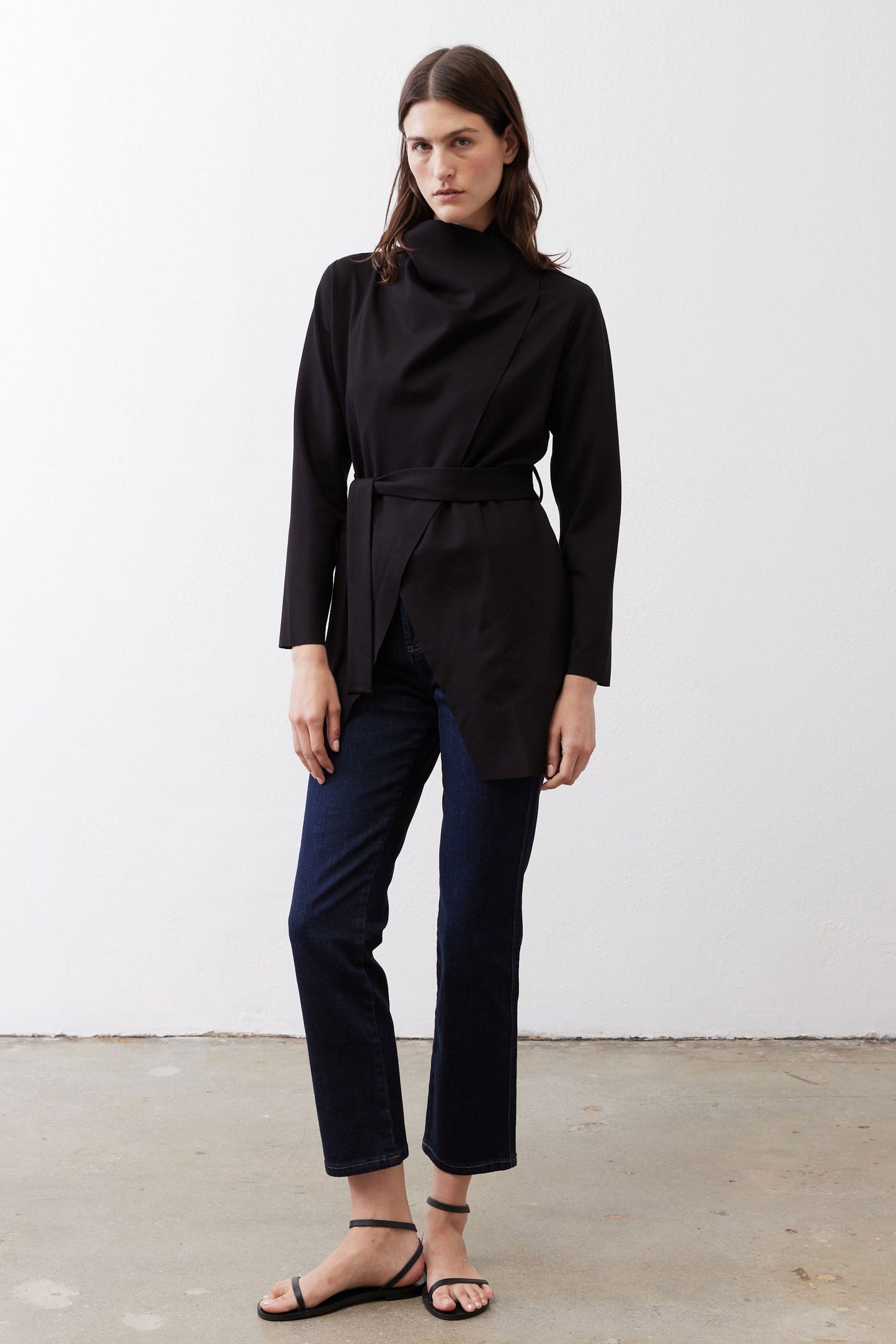Black belted jacket with high collar and long sleeves, front drape detail.