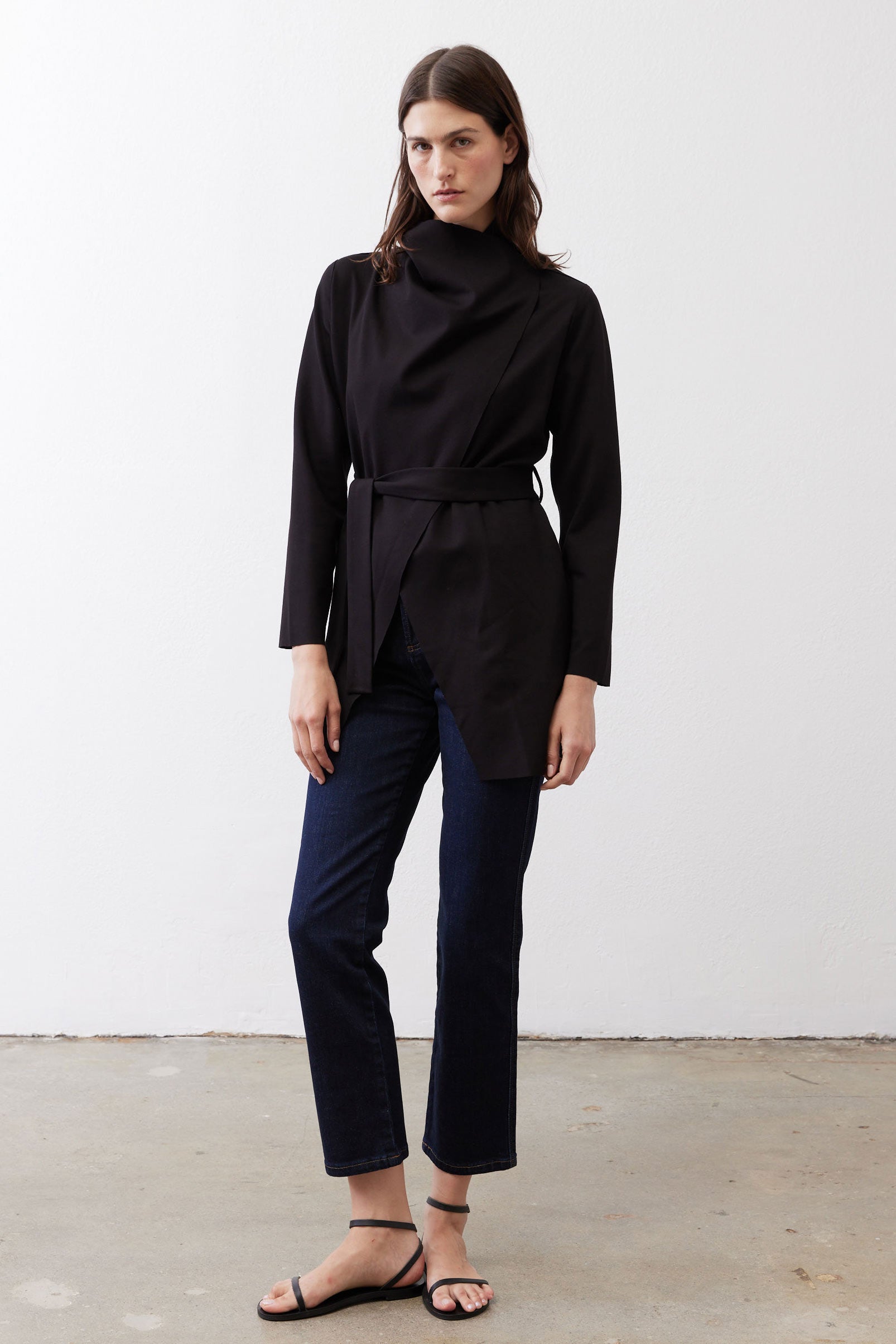 Black belted jacket with high collar and long sleeves, front drape detail.