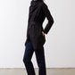 Black wrap jacket with tie belt and long sleeves, worn over dark pants.