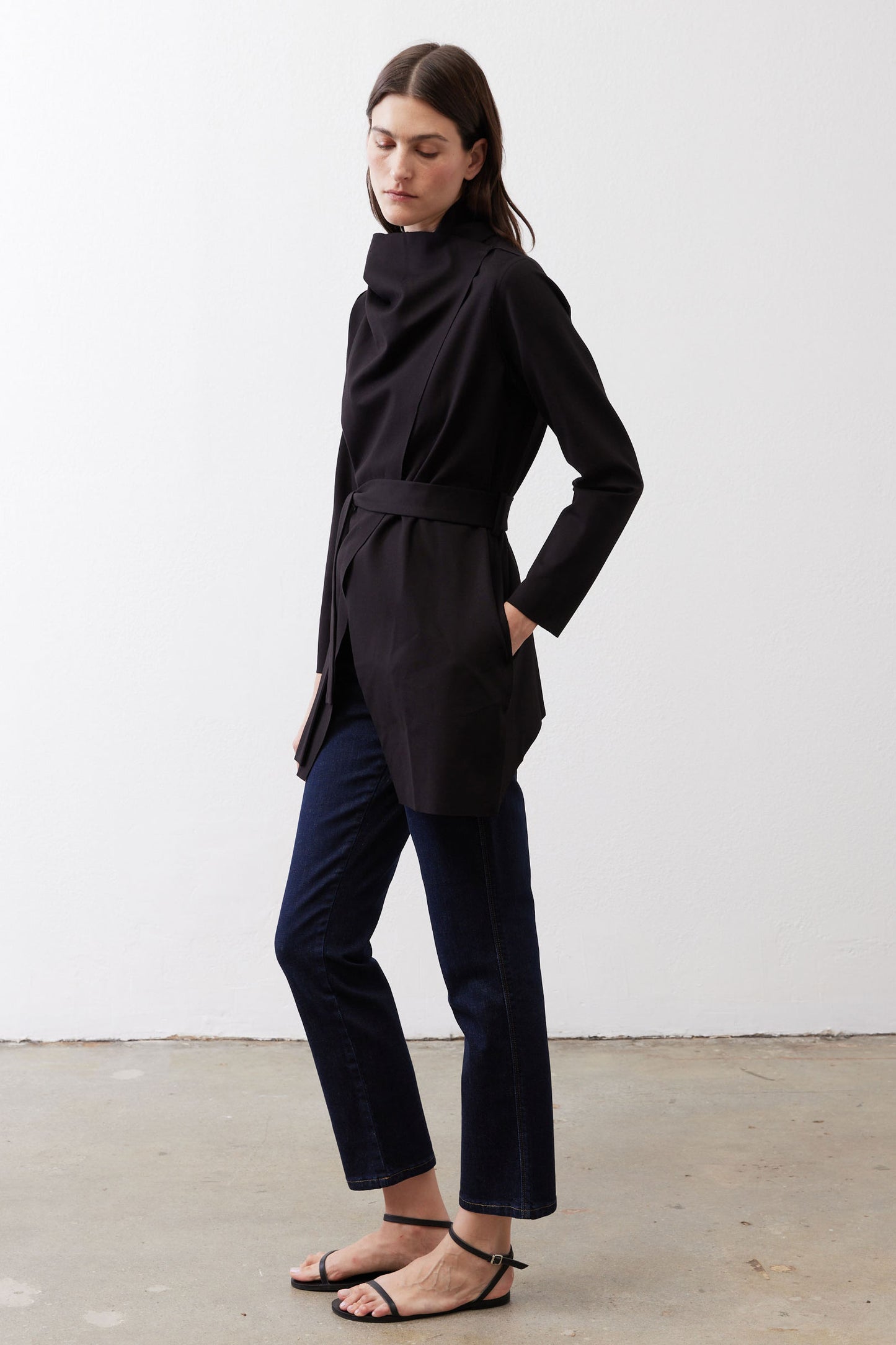 Black wrap jacket with tie belt and long sleeves, worn over dark pants.