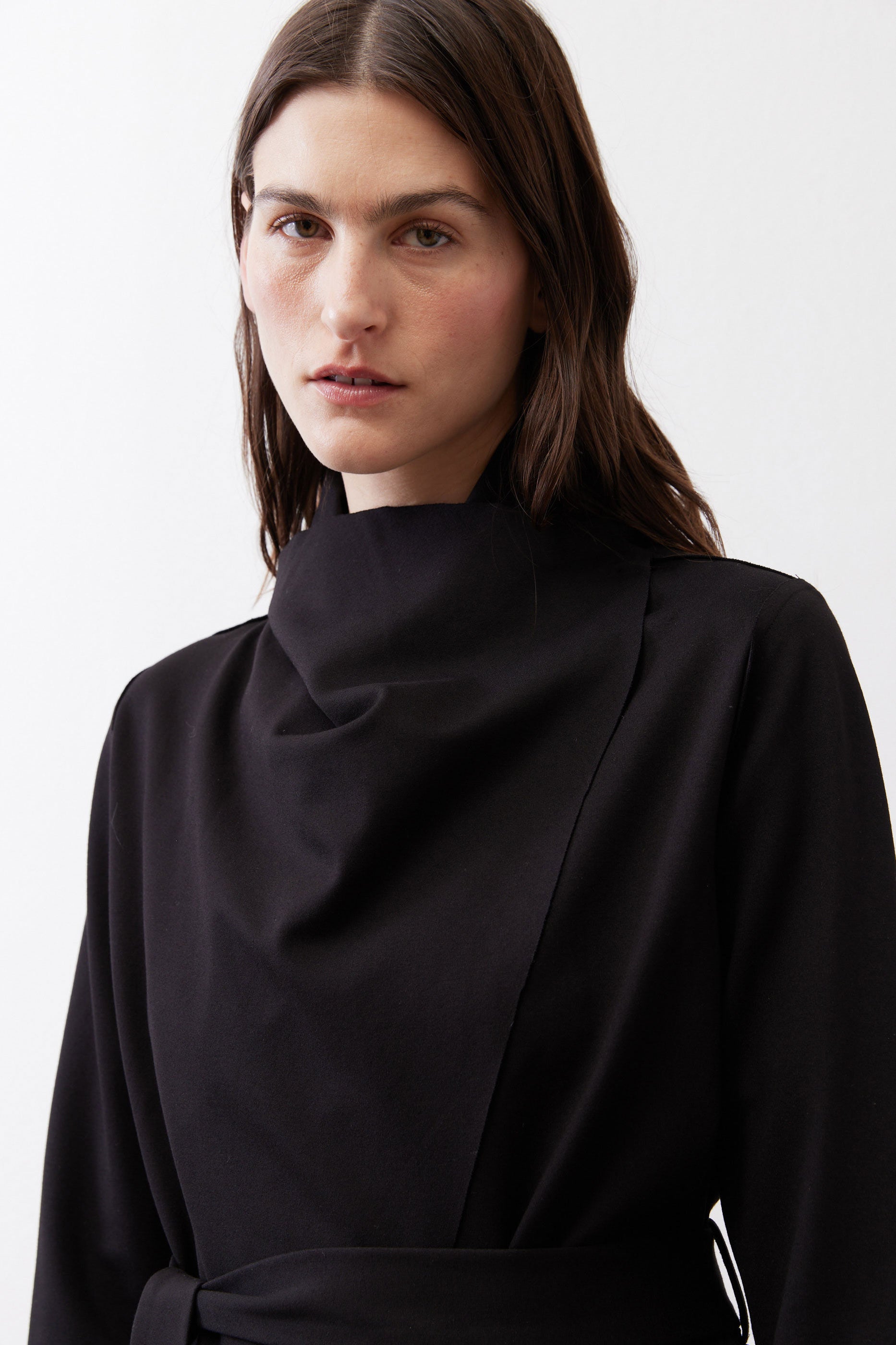 Black high-neck jacket with draped collar and front tie belt.