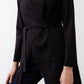 Black jacket close-up: tied waist belt and curved drape at hem.