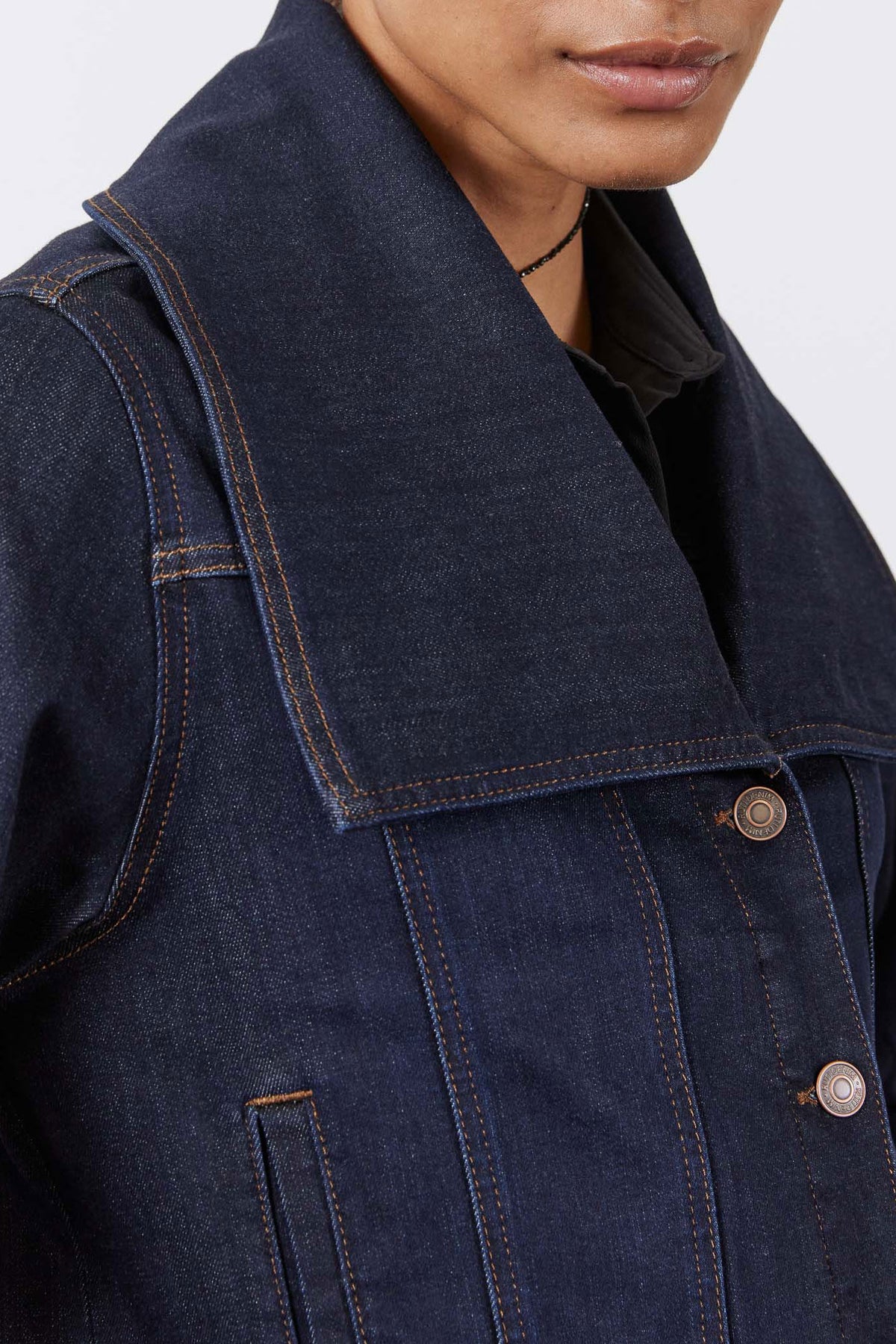 Dark denim jacket chest with button flap pocket and contrasting topstitching