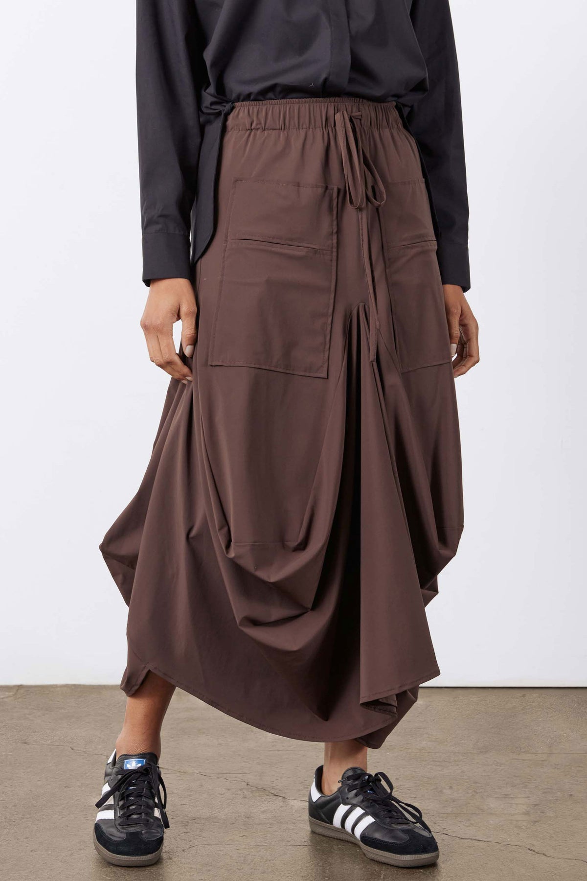 Brown skirt with gathered waist, side cargo pockets, and flowing draped panels
