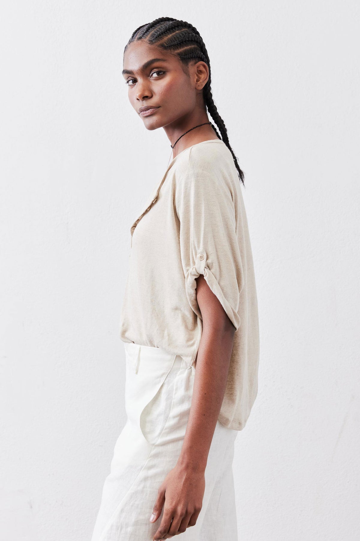 Oat elbow-sleeve half-button top in side view with cuff button detail