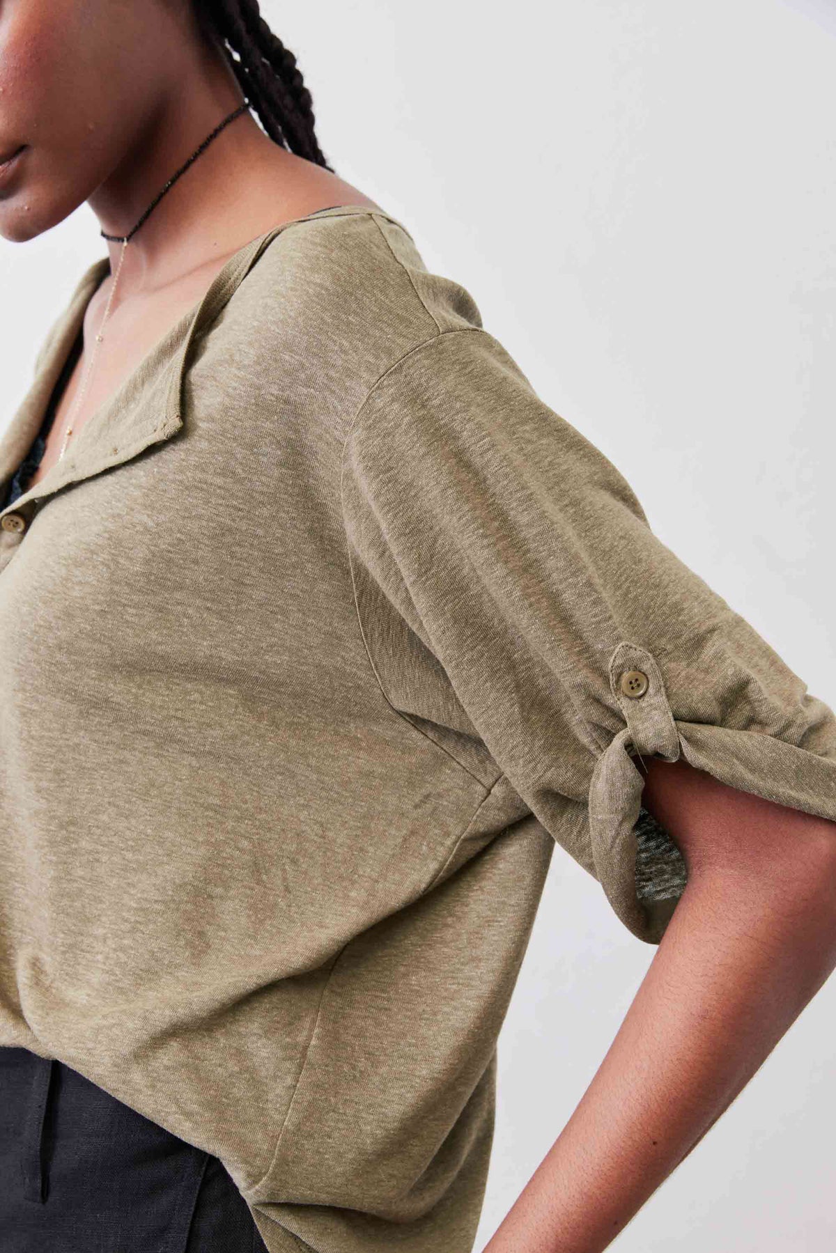 Warm olive elbow-sleeve top detail with half-button placket and sleeve cuff