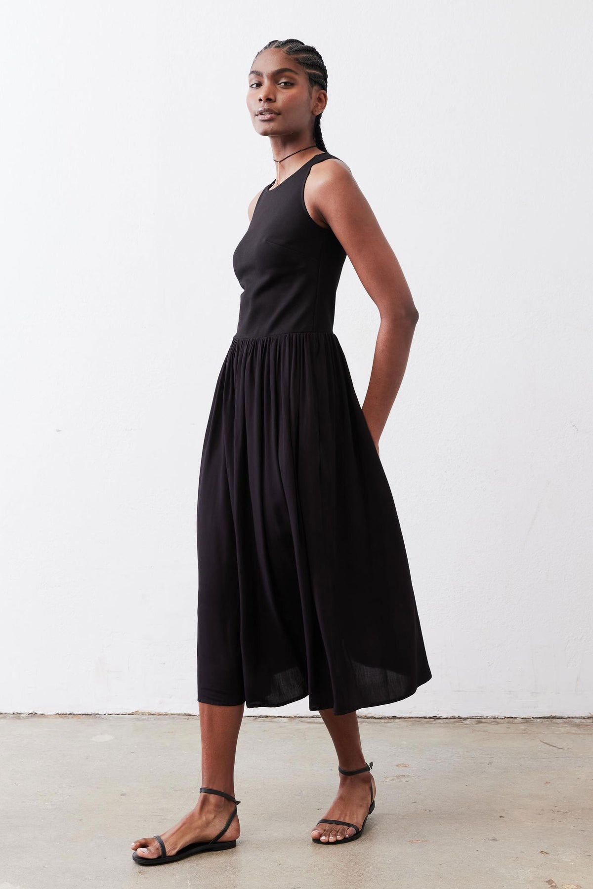 Black sleeveless high-neck tank dress with gathered skirt, side standing