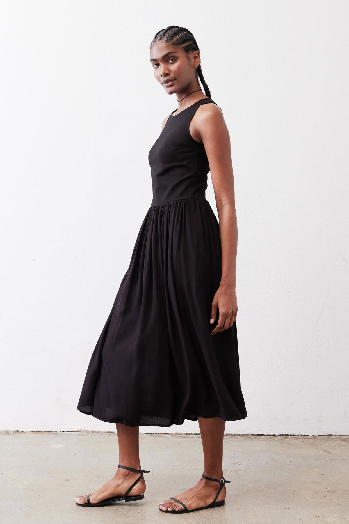 Black high-neck tank dress with gathered skirt, sleeveless midi, angled side