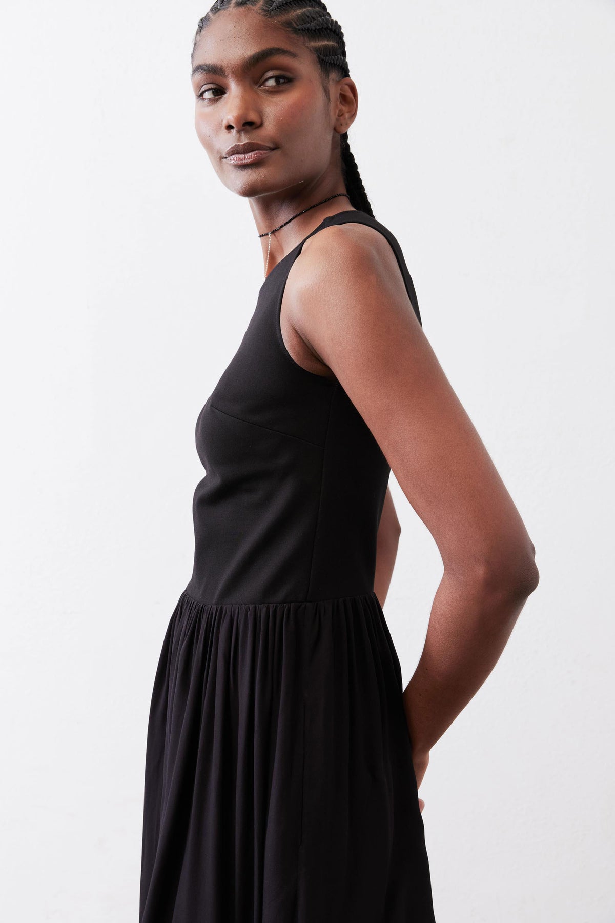 Black high-neck tank dress, sleeveless with gathered skirt, side view