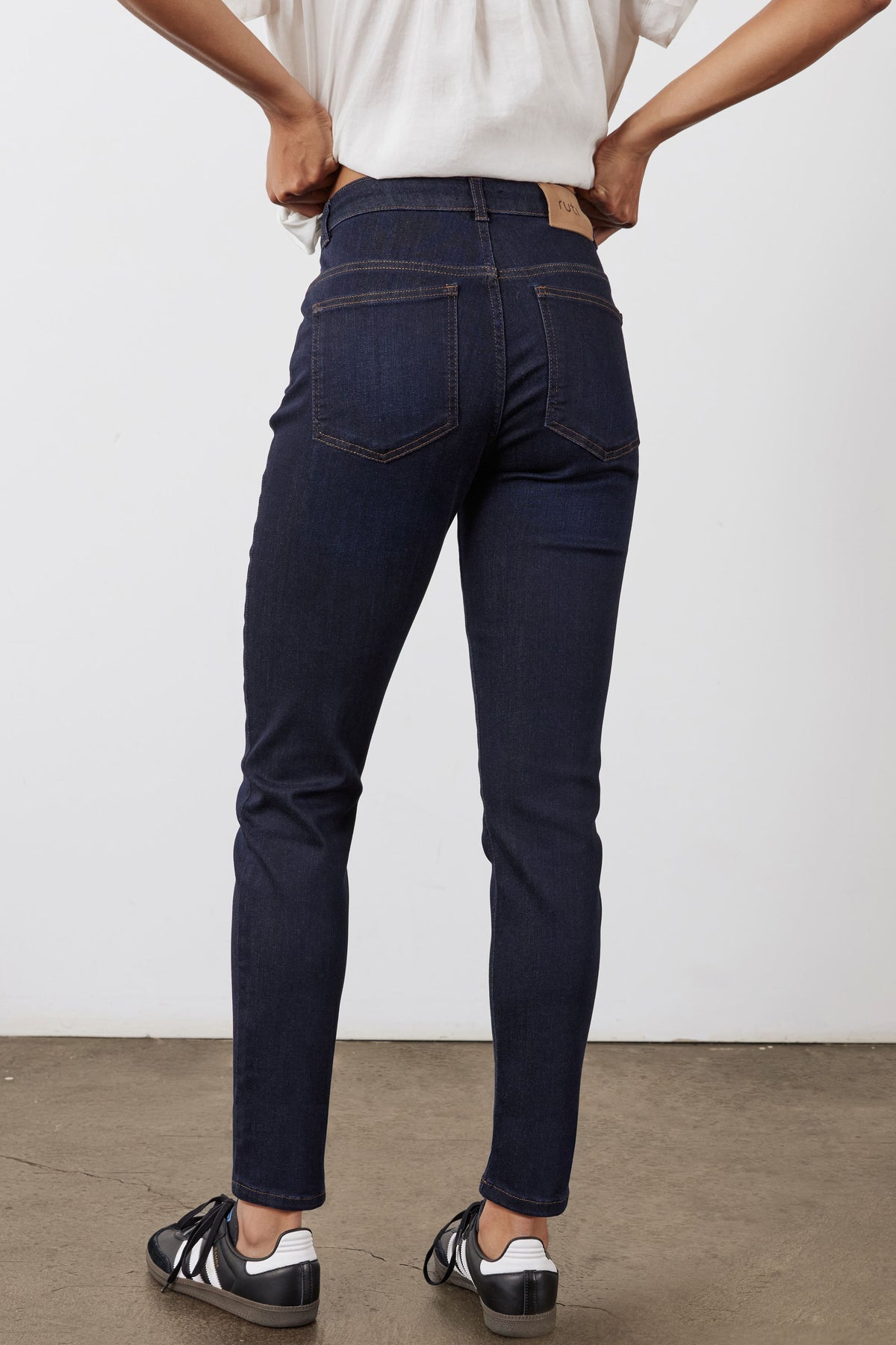 Dark blue fitted jeans back view with belt loops, yoke seam, and five-pocket styling