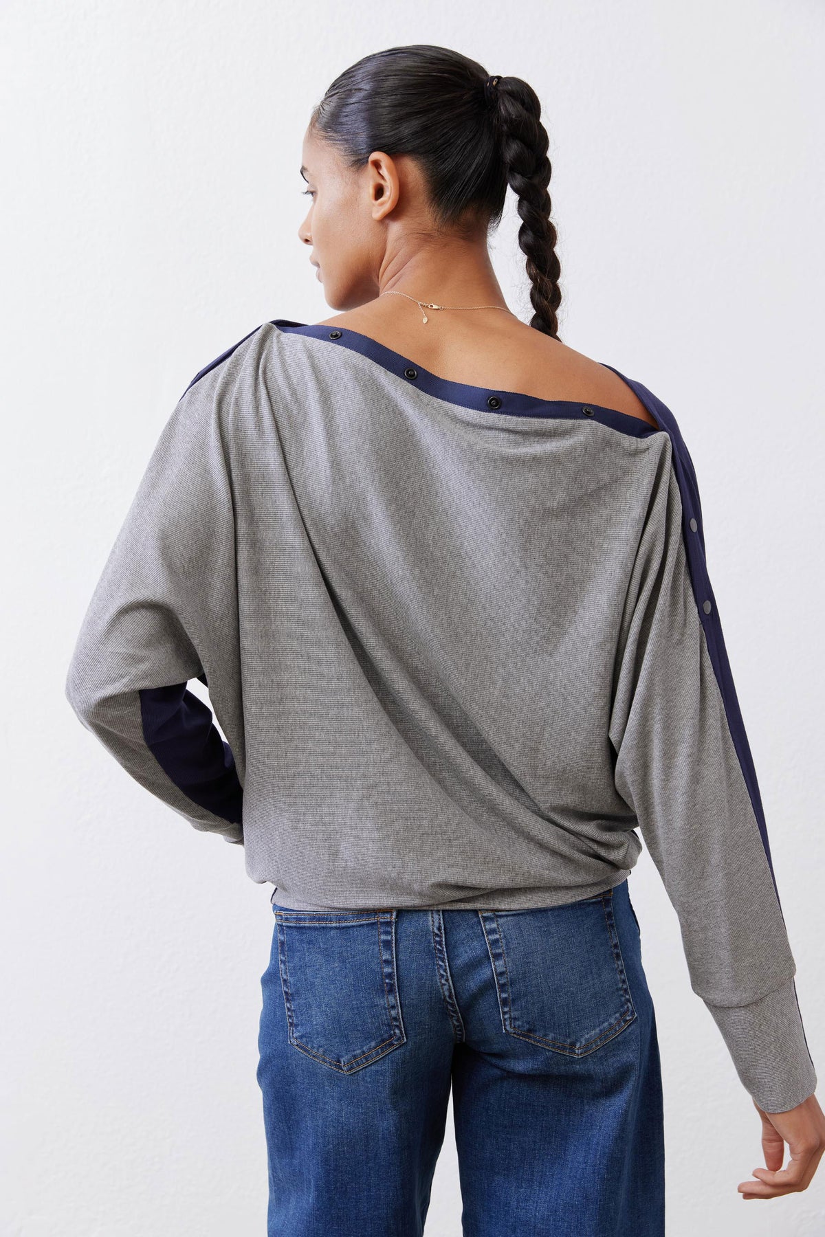 Gray long sleeve top with draped back and navy trim around neckline